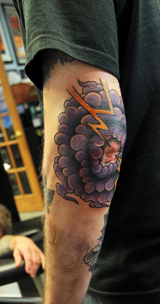tattoo of purple storm clouds and yellow lightning on an elbow  2nd view 