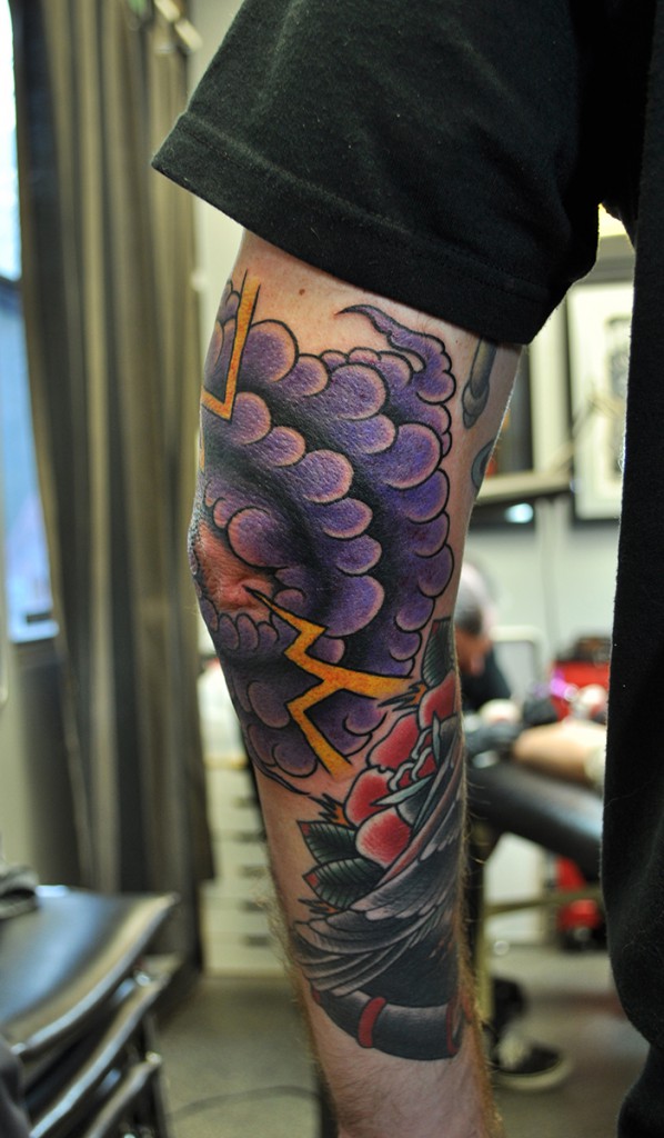 tattoo of purple storm clouds and yellow lightning on an elbow 